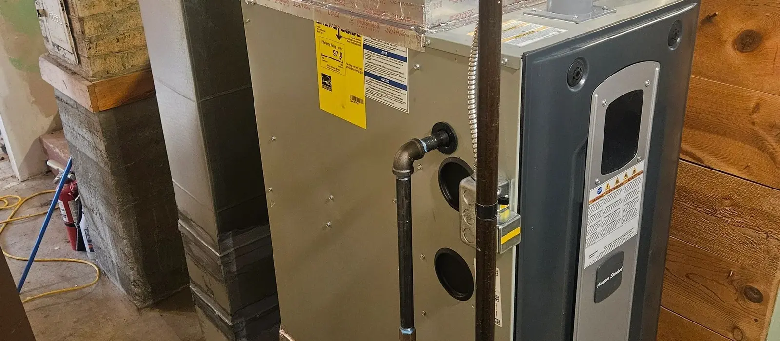 New high-efficiency American Standard gas furnace installed in a basement with a freshly fabricated sheet metal supply plenum and taped transition above it